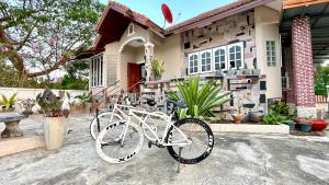 Una bicicleta blanca estacionada frente a una casa en บ้านเพื่อน @อุทัยธานี, en Ban Don Khwang