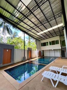 uma piscina com duas cadeiras brancas e uma piscina em Hidayah Condotel,Ao-nang, Krabi em Ban Khlong Haeng