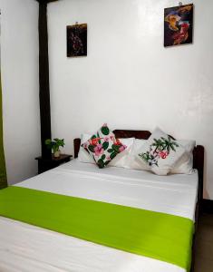 a bed with green and white sheets and pillows at DGA Traveler's Inn in Coron
