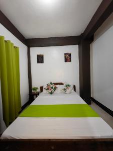 a bedroom with a large bed with green curtains at DGA Traveler's Inn in Coron