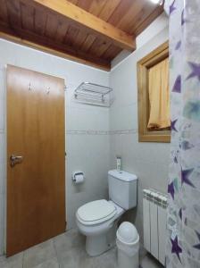 een badkamer met een toilet en een houten deur bij Cabañas Carelmapu in Bariloche