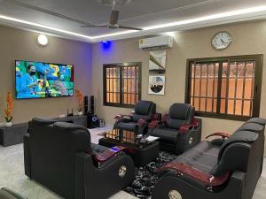 a waiting room with black chairs and a tv at LGH (Luxury Guest House) Résidence in Lomé