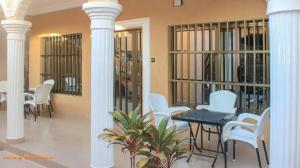 a room with white chairs and a table and columns at LGH (Luxury Guest House) Résidence in Lomé