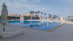 ein großer Swimmingpool mit Sonnenschirm und Liege in der Unterkunft Scandic resort سكانديك ريزورت in Hurghada