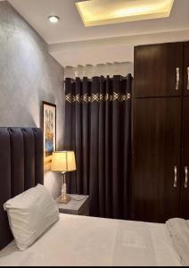 a bedroom with black curtains and a bed and a lamp at 1 bed apartment available in Al nadd in Sharjah