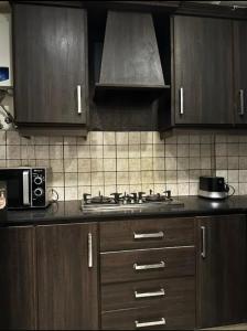 a kitchen with wooden cabinets and a stove top oven at 1 bed apartment available in Al nadd in Sharjah