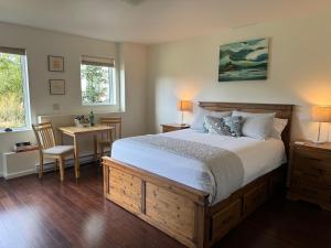 1 dormitorio con 1 cama grande, mesa y sillas en Liahona Guest House en Ucluelet