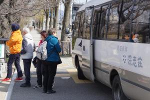 a group of people waiting to get on a bus at Fukashiso in Matsumoto
