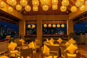 um restaurante com almofadas amarelas, mesas e luzes em Jaya Suites Hotel em Phnom Penh