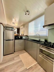una cocina con electrodomésticos de acero inoxidable y una ventana en Tiaki Guesthouse - Cozy Modern Studio - 5min drive from the beach and Punaauia center, en Punaauia