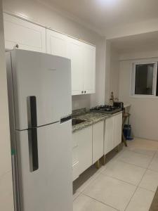 uma cozinha com armários brancos e um frigorífico em Frente ao Mar, Sacada e Garagem em Solemar