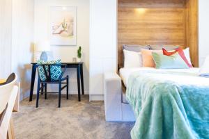 a bedroom with a bed and a desk with a chair at City Living: Upper Studio Haven on Wilmer in Christchurch