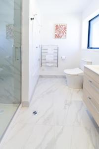 a white bathroom with a shower and a toilet at City Living: Upper Studio Haven on Wilmer in Christchurch +26 photos