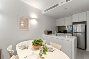 a kitchen and dining room with a white table and chairs at A Chic & Comfy 2BR Apt Near Federation Square in Melbourne