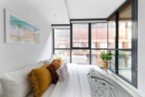 a white couch in a room with large windows at A Chic & Comfy 2BR Apt Near Federation Square in Melbourne