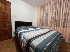 1 dormitorio con cama y cortina en Departamento cerca a centros comerciales, en Cajamarca