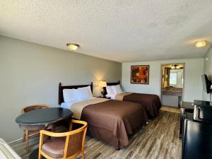 a hotel room with two beds and a table at Knights Inn Bridgeport Frankenmuth in Bridgeport