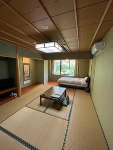 a living room with a table and a bed at ファスティングホテル海の杜 in Kannami