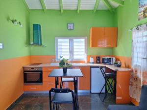 a kitchen with orange and green walls and a table and chairs at Villa confortable 45m² in Anse-Bertrand