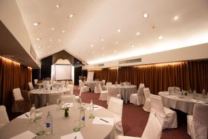 a conference room with white tables and chairs and a screen at Eurasia Chiang Mai Hotel in Chiang Mai