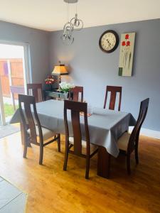 a dining room table with chairs and a clock on the wall at The Meadows House Cobh in Cobh