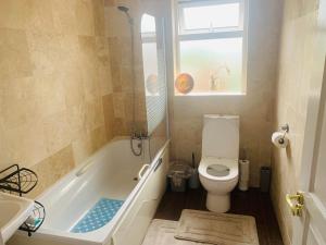 a bathroom with a toilet and a tub and a window at The Meadows House Cobh in Cobh