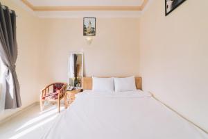 1 dormitorio con 1 cama blanca y 1 silla en KHÁCH SẠN TUẤN KIỆT en Dalat