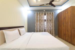 um quarto com uma grande cama branca e uma ventoinha de tecto em श्री राम होटल em Gorakhpur