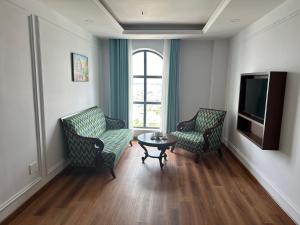 sala de estar con 2 sillas, mesa y TV en Ngoc Thu Palace, en Soc Trang