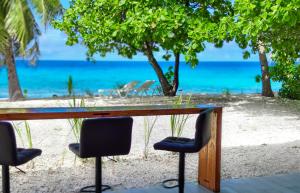 - une table sur la plage avec des chaises et l'océan dans l'établissement Blue Lagoon Villa, à Avatoru