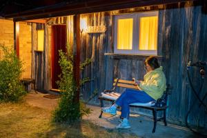 a woman sitting on a bench outside of a house at Fernbrook Cottage in Marrangaroo