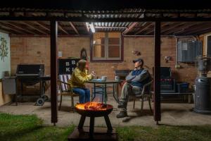 a man and woman sitting at a table in a patio at Fernbrook Cottage in Marrangaroo