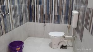baño con aseo blanco y cubo púrpura en Ayodhya-couple friendly Hotel by prithvi yatra hotel, en Ayodhya