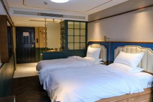 a bedroom with two beds with white sheets at Xinyu Hotel - Shanghai Jiao Tong University Xinhua Road in Shanghai