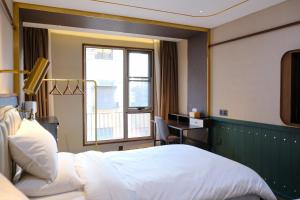 a bedroom with a bed and a desk and a window at Xinyu Hotel - Shanghai Jiao Tong University Xinhua Road in Shanghai