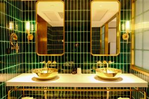 W wyłożonej zielonymi kafelkami łazience znajdują się 2 umywalki i lustra. w obiekcie Xinyu Hotel - Shanghai Jiao Tong University Xinhua Road w Szanghaju