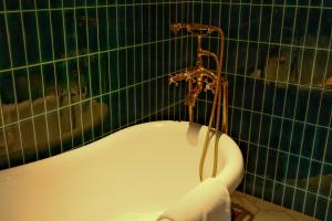 a bath tub in a green tiled bathroom at Xinyu Hotel - Shanghai Jiao Tong University Xinhua Road in Shanghai