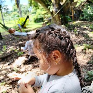 a little girl with braided hair sitting on the ground at Campo Duro Ecolodge in Puerto Villamil