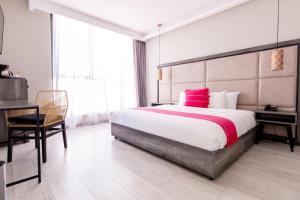 Cette chambre comprend un grand lit avec des oreillers roses et un bureau. dans l'établissement Arkana Grupo Amber - Collection O, à Puebla