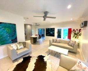 a living room with couches and a ceiling fan at Aquatica - Luxe Holiday Home in Palm Cove
