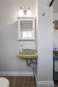 baño con lavabo verde y espejo en Victorian Suite l Heritage Home l Sleep 4 l 55 TV, en Cranbrook