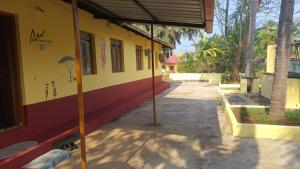 a yellow and red building with a sidewalk at Hallimane Homestay in Udupi