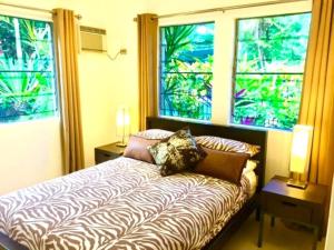 a bedroom with a couch and two windows at Aquatica - Luxe Holiday Home in Palm Cove