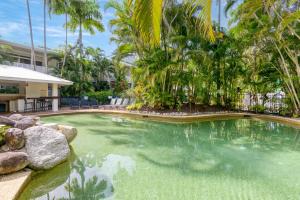 a swimming pool in a resort with palm trees at Ocean Palms Apartments in Port Douglas