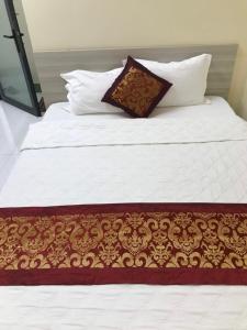 ein weißes Bett mit einer braunen und weißen Decke und Kissen in der Unterkunft KHÁCH SẠN NGUYỄN LONG in Ấp Tháp Mười