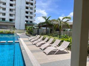 a row of white lounge chairs next to a swimming pool at Comfy unit with fast wifi along Lacson St. in Bacolod