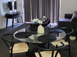 a living room with a glass table and chairs at Merrylands Hidden Gem! one Bedroom Apartment in Merrylands