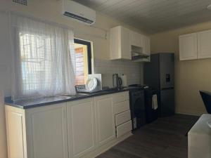 a kitchen with white cabinets and a black refrigerator at Cozy Kalundu Apartment in Lusaka