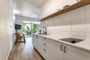 una cocina con armarios blancos y fregadero en Ocean Palms Apartments en Port Douglas
