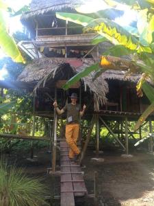 a man standing in front of a house with an umbrella at Jungle Lodge with lookout tower in Pucallpa